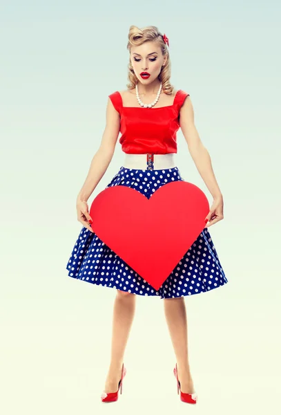 Smiling woman holding heart symbol, dressed in pin-up style — Stock Photo, Image