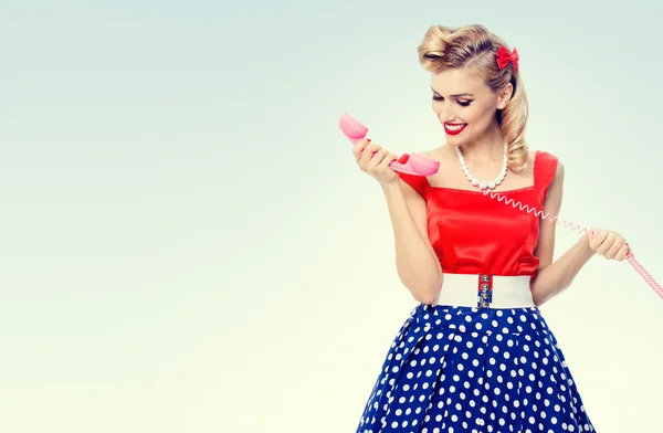 Усміхнена жінка з телефоном, одягнена в плаття в стилі пін-ап — стокове фото