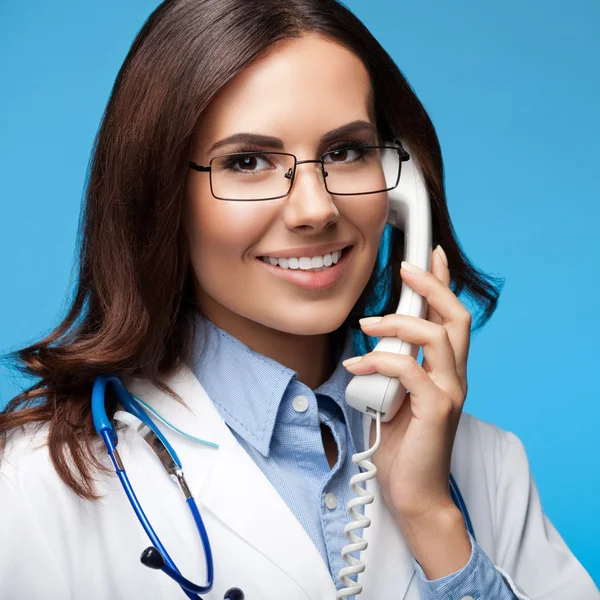 Uśmiechający się młody lekarz z telefonu, na niebiesko — Zdjęcie stockowe