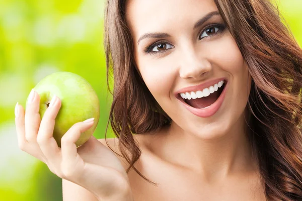 Giovane donna felice sorridente con mela, all'aperto — Foto Stock