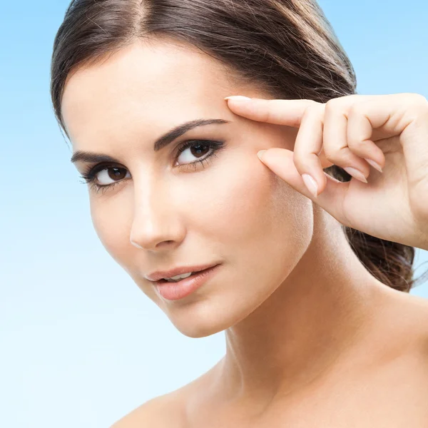 Woman touching skin or applying cream, blue Stock Picture