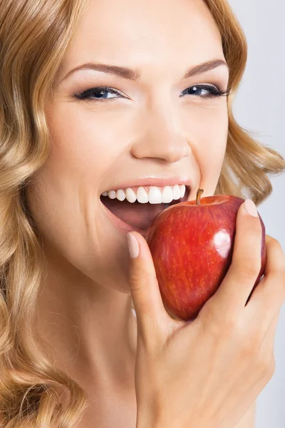 Frau isst Apfel, auf grau — Stockfoto