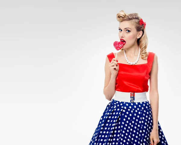Mladá žena jíst barevné lízátko, oblečený v pin-up styl — Stock fotografie