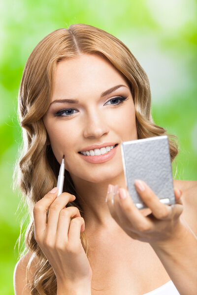 Smiling woman with make up brush, outdoor