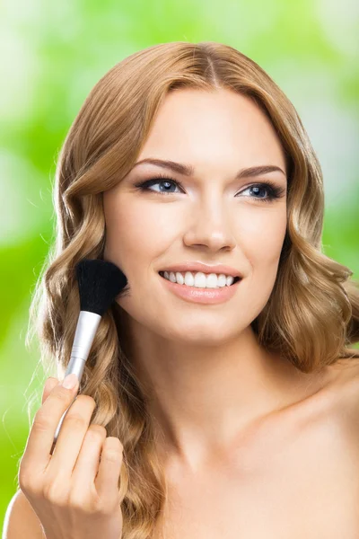 Lächelnde Frau mit Make-up Pinsel, im Freien — Stockfoto