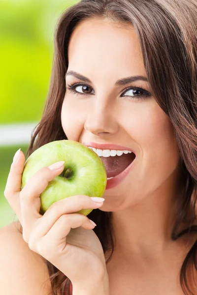 Mujer joven comiendo manzana, al aire libre — Foto de Stock