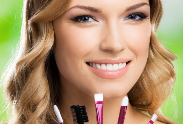 Donna sorridente con strumenti per il trucco, all'aperto — Foto Stock