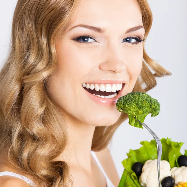 Woman eating broccoli, over gray — Stock Photo, Image