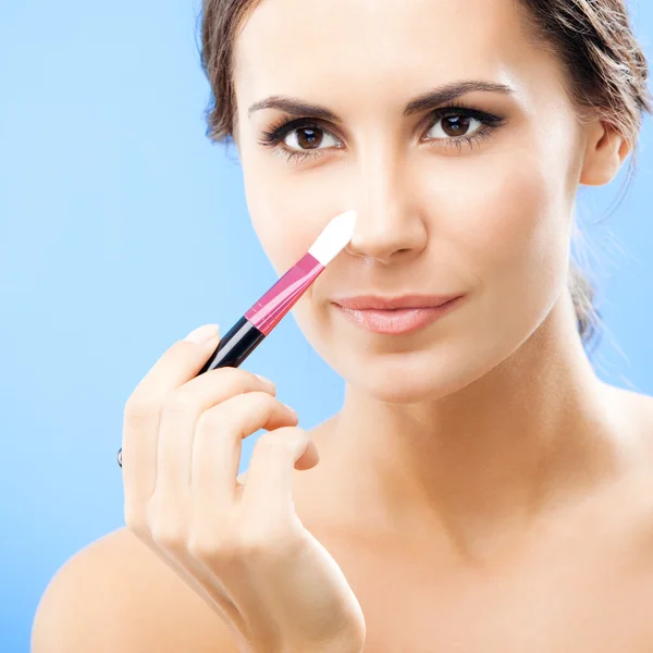 Woman with cosmetics brush, on blue — 스톡 사진