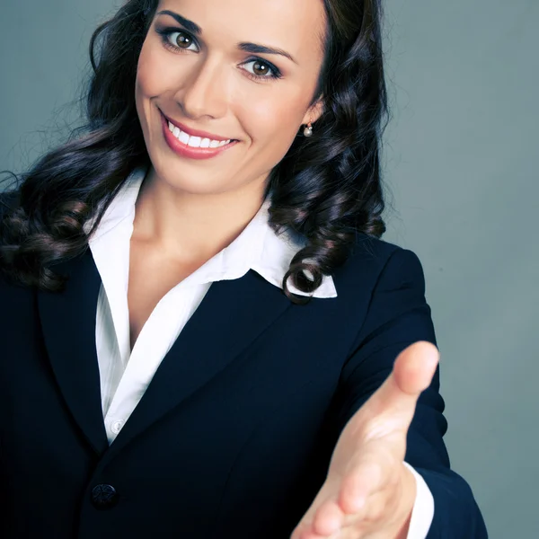 Businesswoman giving hand for handshake, over grey — Stock Photo, Image