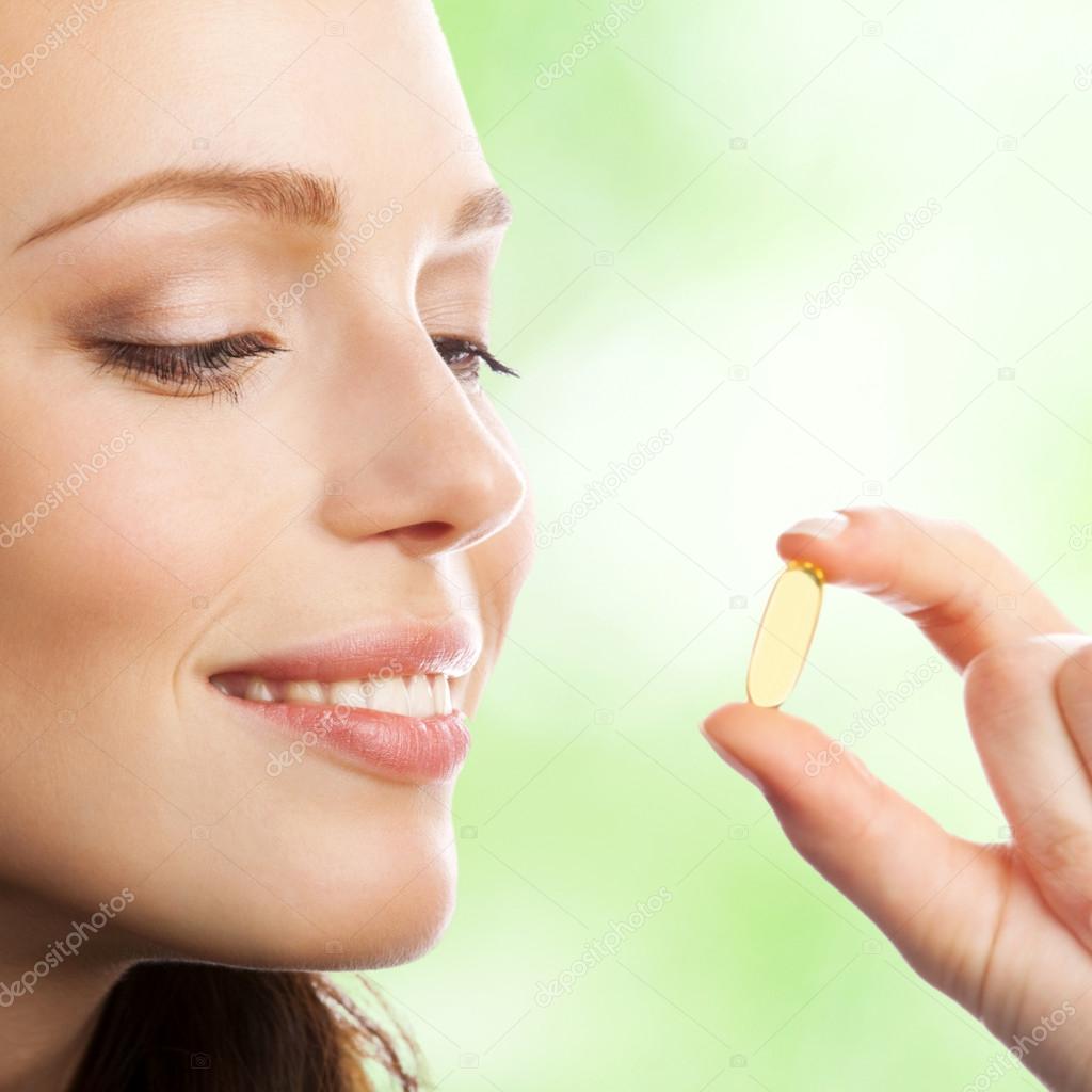 Woman with Omega 3 fish oil capsule, outdoor