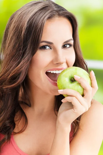 Mujer joven comiendo manzana, al aire libre — Foto de Stock