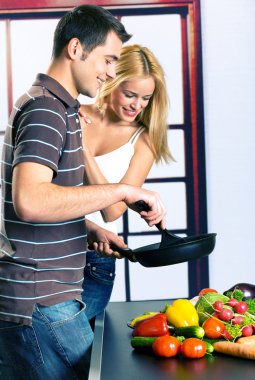 Young attractive happy smiling couple playfully cooking at kitch clipart