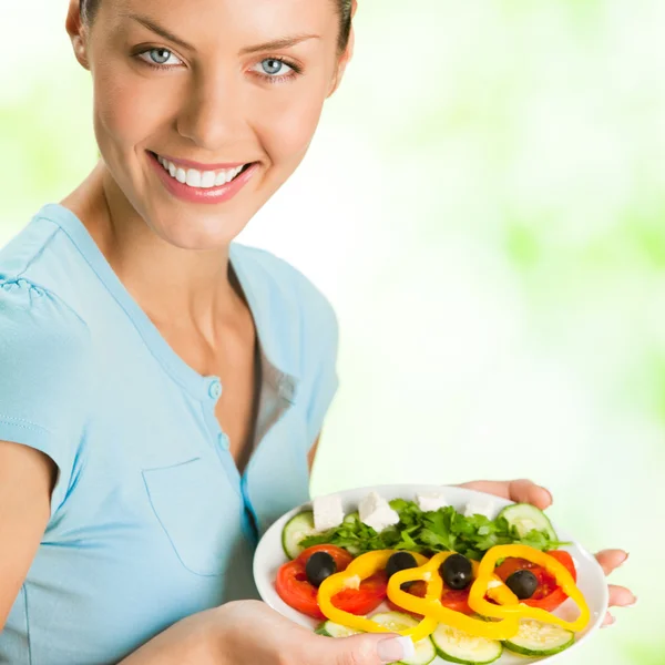 Улыбающаяся женщина с салатом, на открытом воздухе — стоковое фото