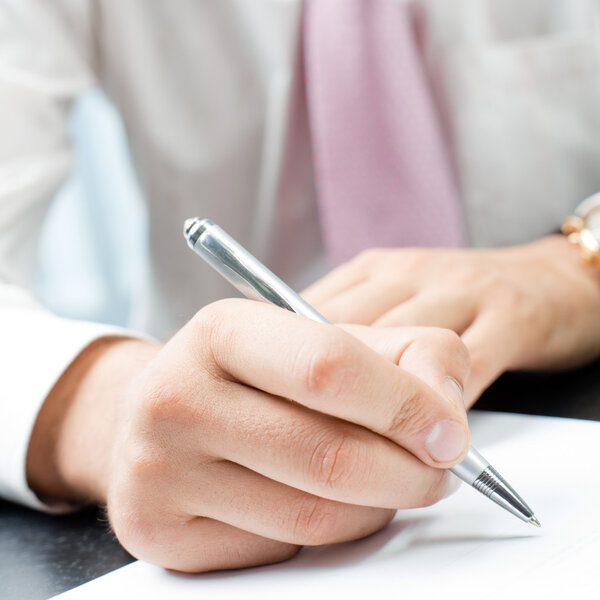 Closeup of writing businessman with document