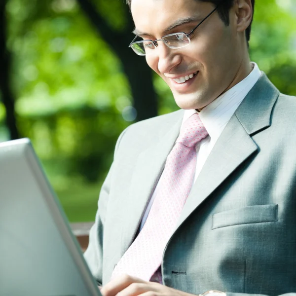 Jonge lachende zakenman werken met laptop — Stockfoto