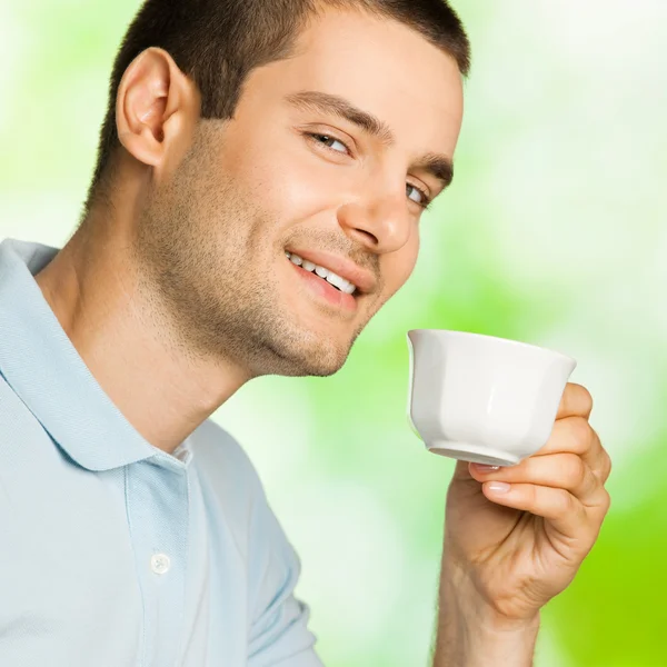 Ritratto di giovane felice uomo sorridente che beve caffè, all'aperto — Foto Stock