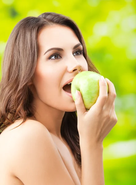 Молода жінка їсть яблуко, на відкритому повітрі — стокове фото