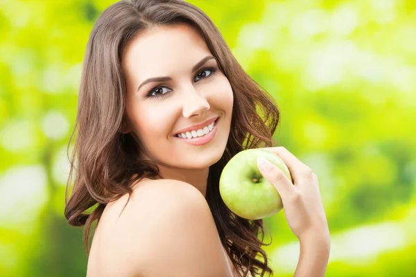 Молода жінка їсть яблуко, на відкритому повітрі — стокове фото