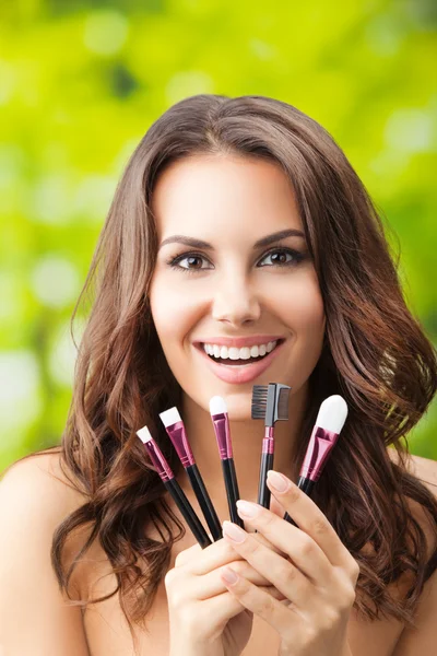 Mulher sorridente com ferramentas de maquiagem, ao ar livre — Fotografia de Stock