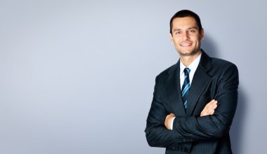 Gri karşı çapraz kolları olan mutlu işadamı