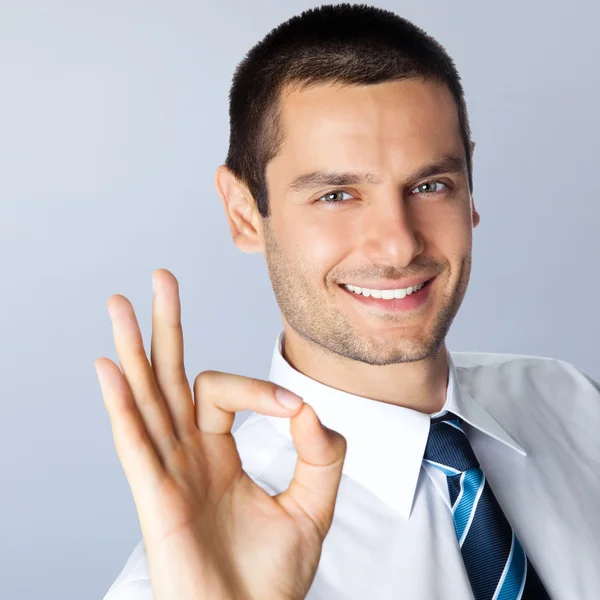 Businessman with okay gesture, against grey — Stock Photo, Image