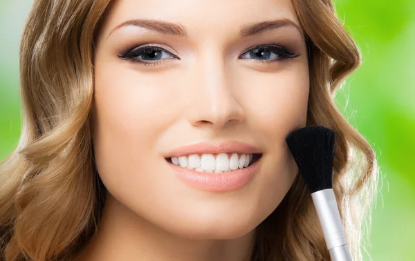 Smiling woman with make up brush, outdoor — Stock Photo, Image