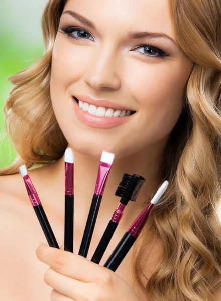 Mujer sonriente con herramientas de maquillaje, al aire libre —  Fotos de Stock