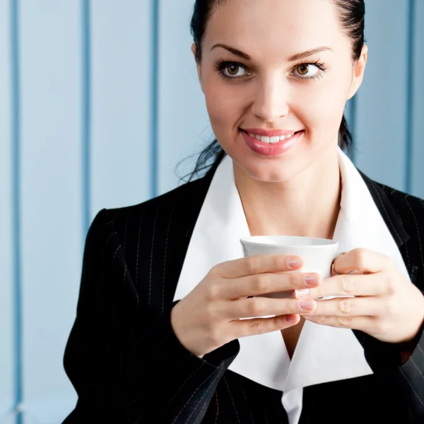 Heureuse femme d'affaires avec ordinateur portable buvant du café au bureau — Photo