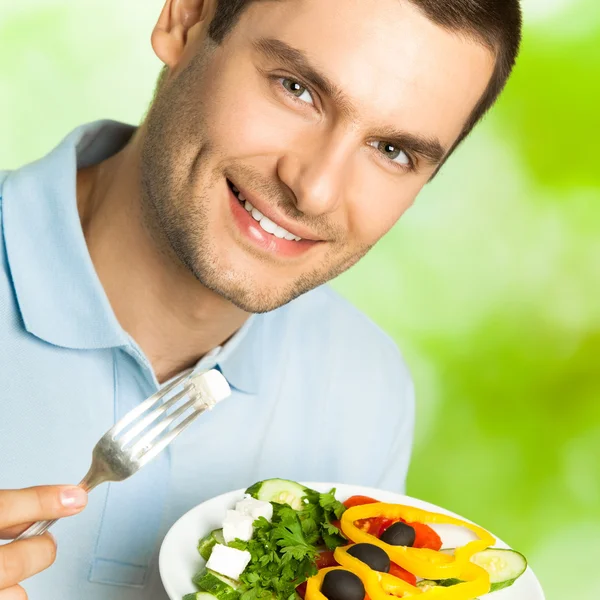 Joven hombre feliz comiendo ensalada, al aire libre —  Fotos de Stock