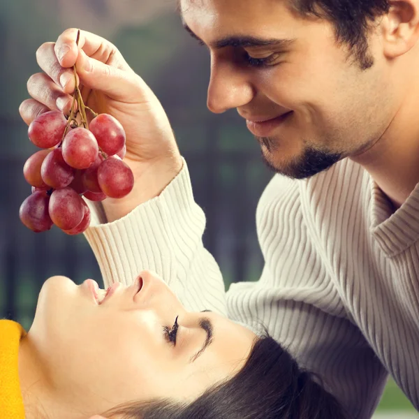 Portrait de jeune couple mangeant des raisins, en plein air — Photo