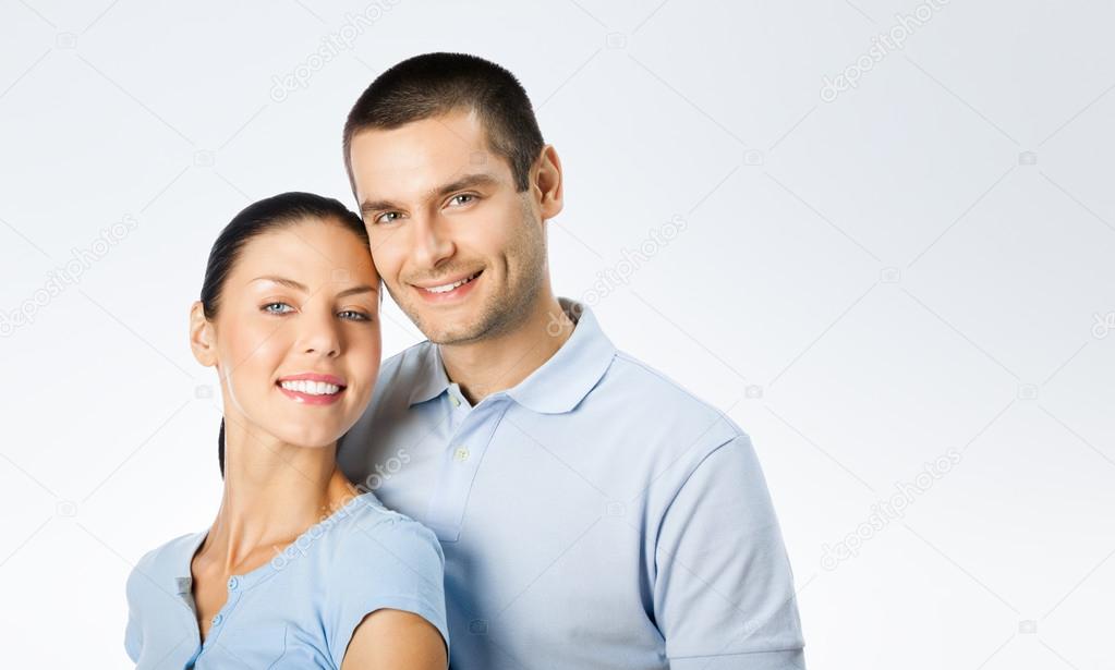 Cheerful amorous young couple, on grey