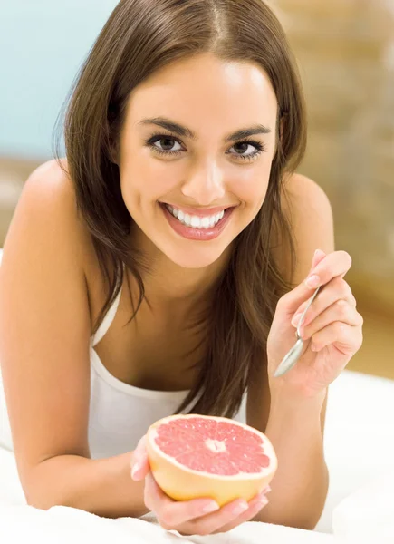 Portarit of young woman eating grapefruit — Stock Photo, Image