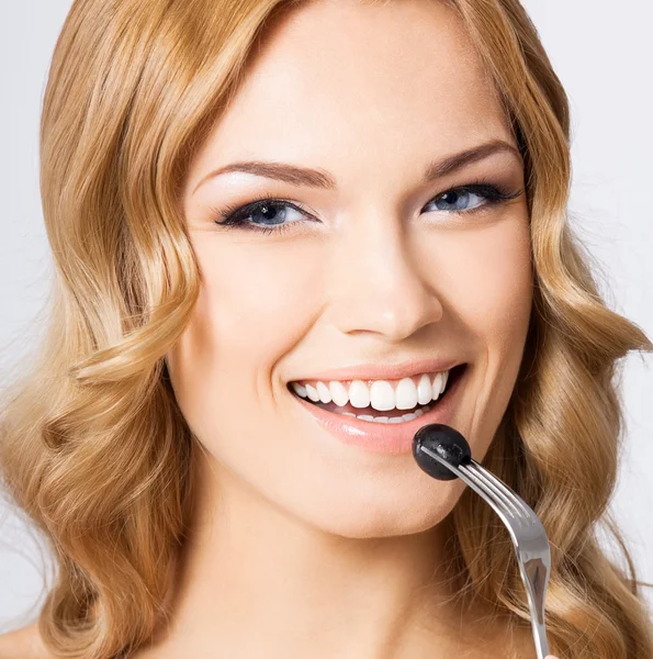 Young woman eating black olive, on grey — Stock Photo, Image