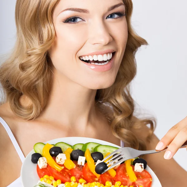 Portrait of young woman with vegetarian salad, on grey — Stock Photo, Image