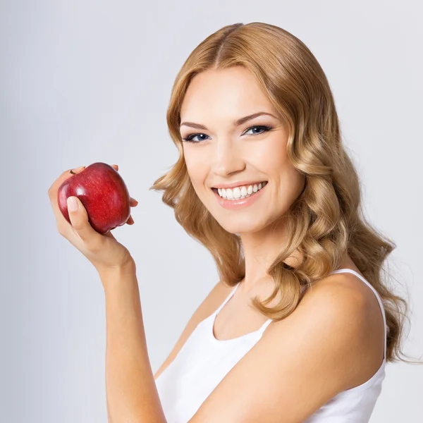 Mujer joven con manzana roja, sobre gris — Foto de Stock