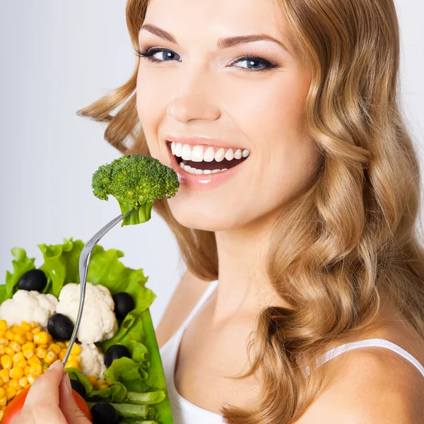 Portrait of young woman with vegetarian salad, on grey Royalty Free Stock Images