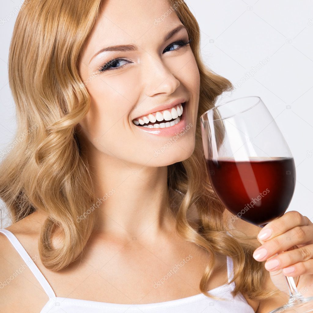 Young happy woman with glass of red wine, on gray