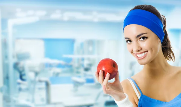 Young smiling woman with apple, at gym — Stock Photo, Image