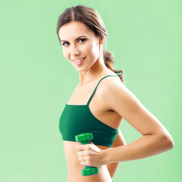 Woman in fitness wear with dumbbell, on green — Stock Photo, Image