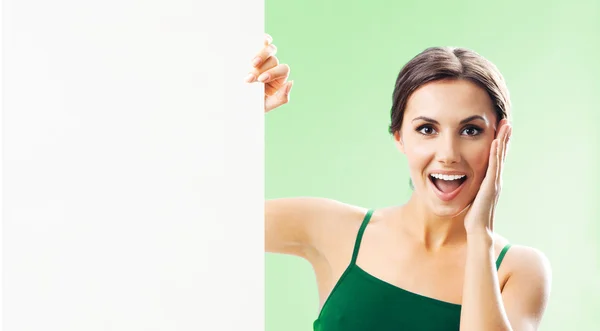Woman in fitnesswear showing signboard, on green — Stock Photo, Image