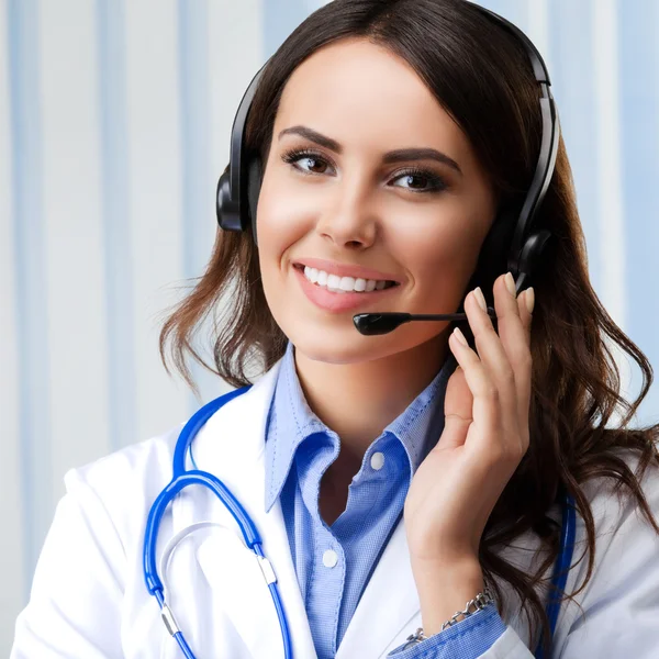 Lachende vrouwelijke arts in de hoofdtelefoon, op kantoor — Stockfoto