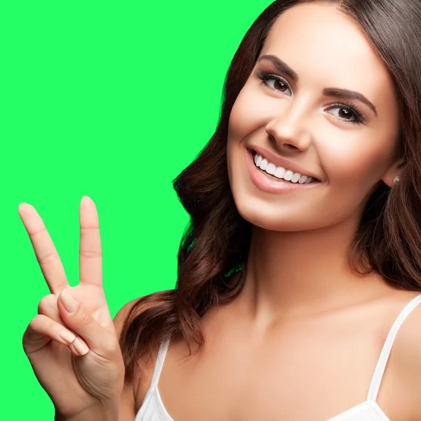 Žena ukazuje dva prsty nebo vítězství gesto, na zelené barvy ke — Stock fotografie