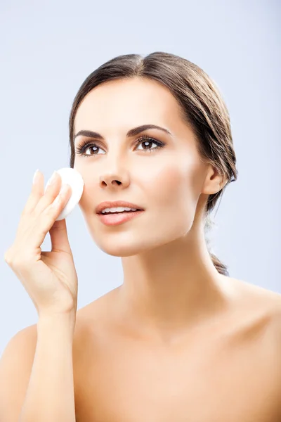 Young woman cleaning skin by cotton pad, over grey — Stock Photo, Image