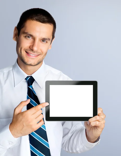 Šťastný podnikatel zobrazeno prázdné počítače tablet pc, přes šedá — Stock fotografie