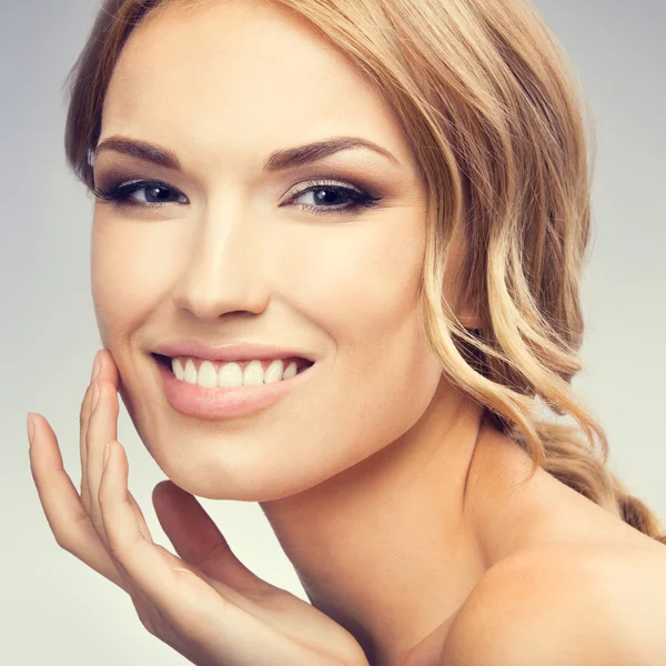 Sonriente mujer rubia alegre tocando la piel o aplicando crema —  Fotos de Stock