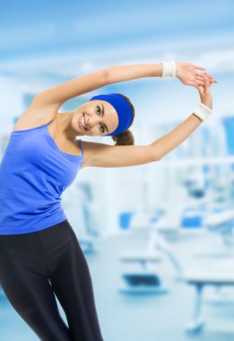Young happy woman doing fitness exercises, at fitness club