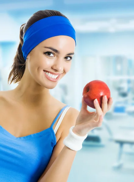 Kvinna i sportkläder med rött äpple, på gym — Stockfoto