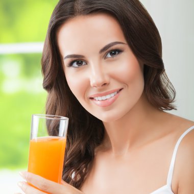 mutlu gülümseyen genç kadın portakal suyu içme