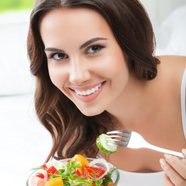 gülümseyen genç kadın yatakta salata, yemek